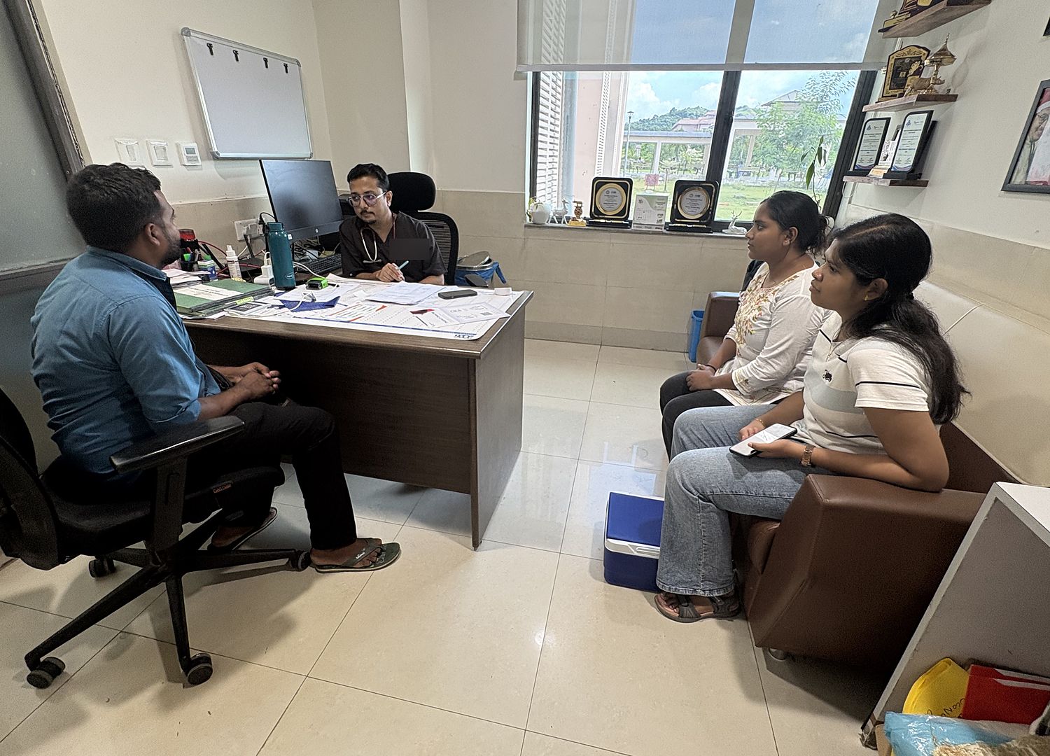 Members of the lab in discussion with a clinician across a desk in a departmental office at AIIMS Guwahati.