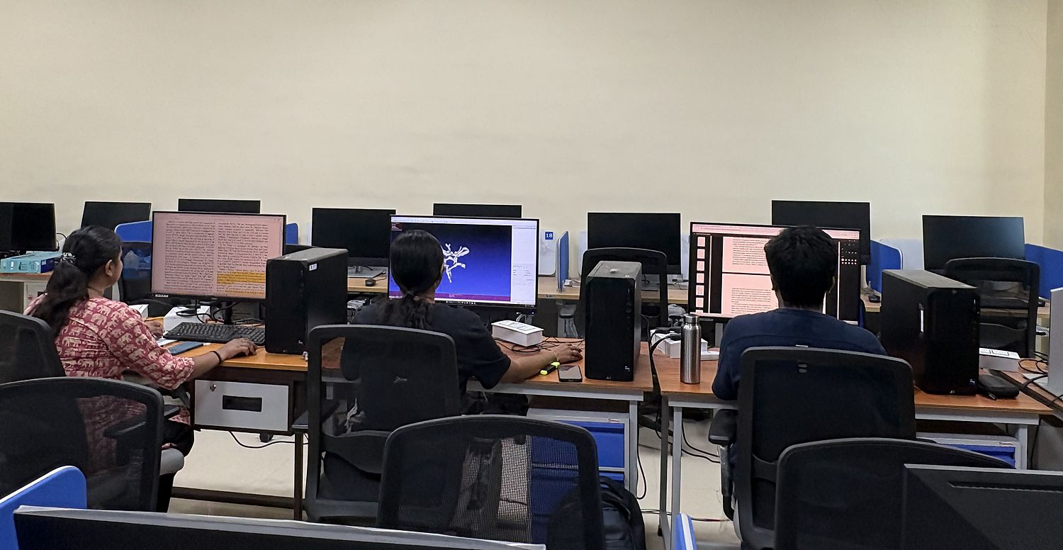 Three members of the lab at workstations in the shared computing room, with papers and a vascular model on the screens.